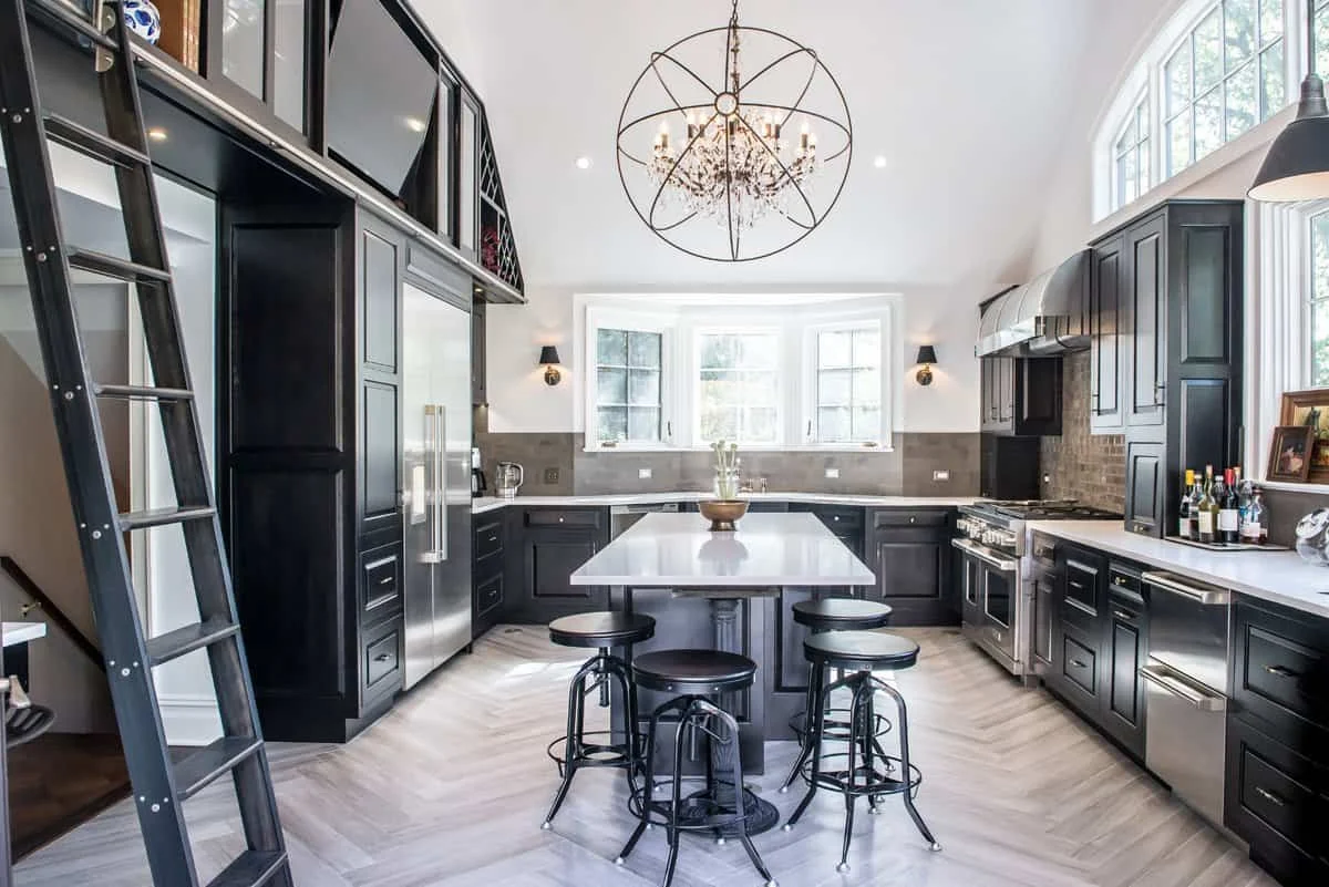 Award-winning kitchen remodel in Pelham Manor NY with dark cabinetry, large island seating, and statement chandelier