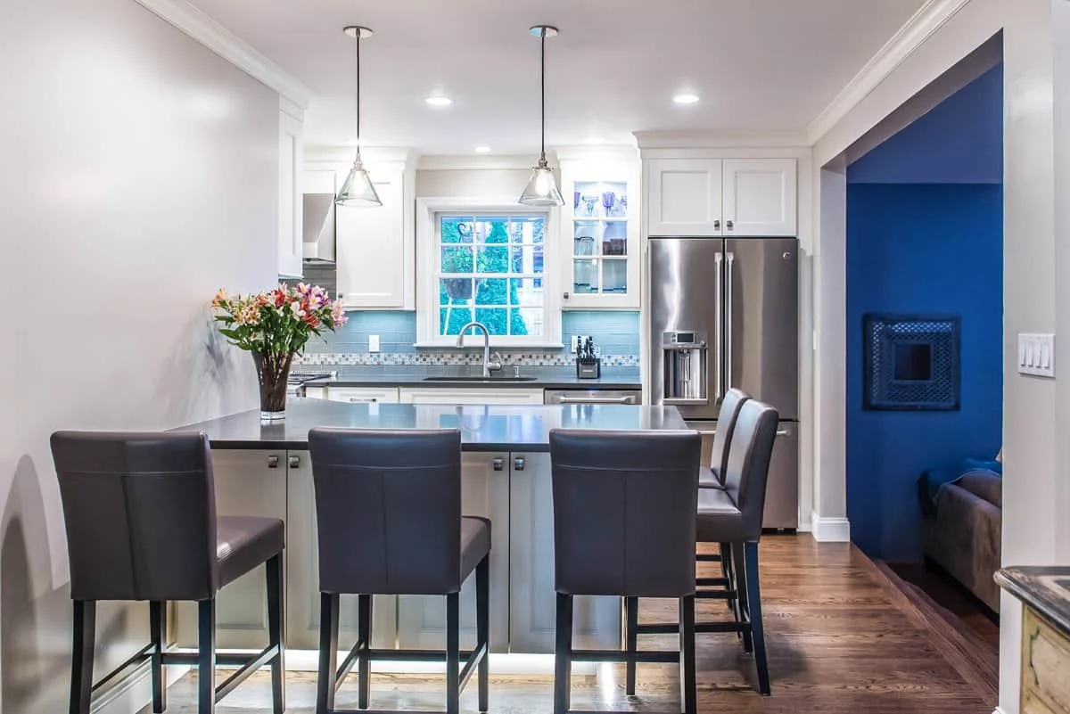 White custom kitchen with toe kick lighting, including 5 seating around Island