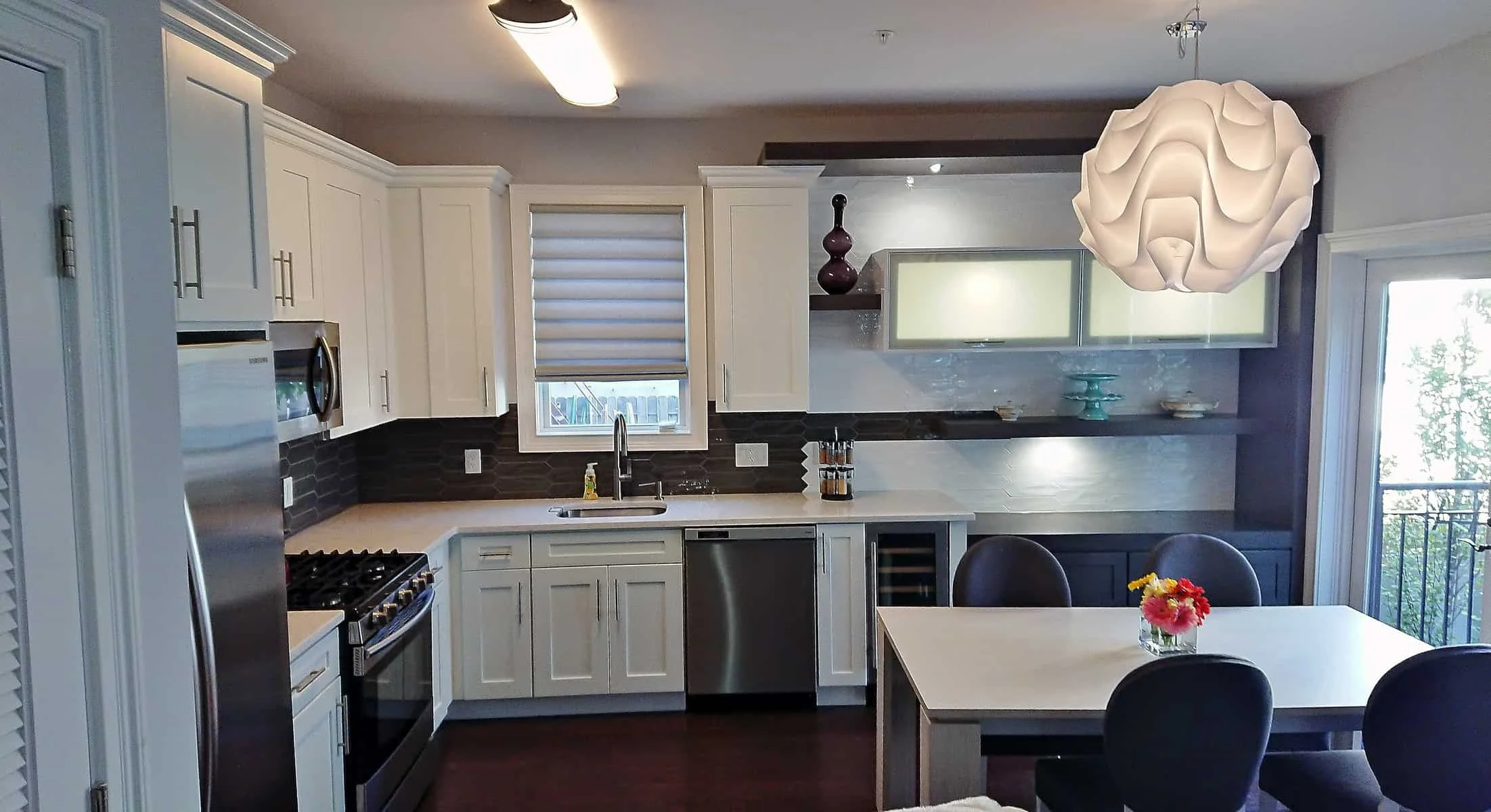 Modern white kitchen with island seating, pendant lighting, and stainless steel appliances