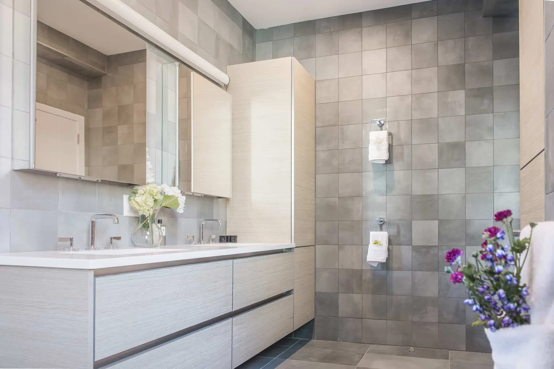 Modern bathroom vanity with floating drawers, integrated sink, and gray tiled wall