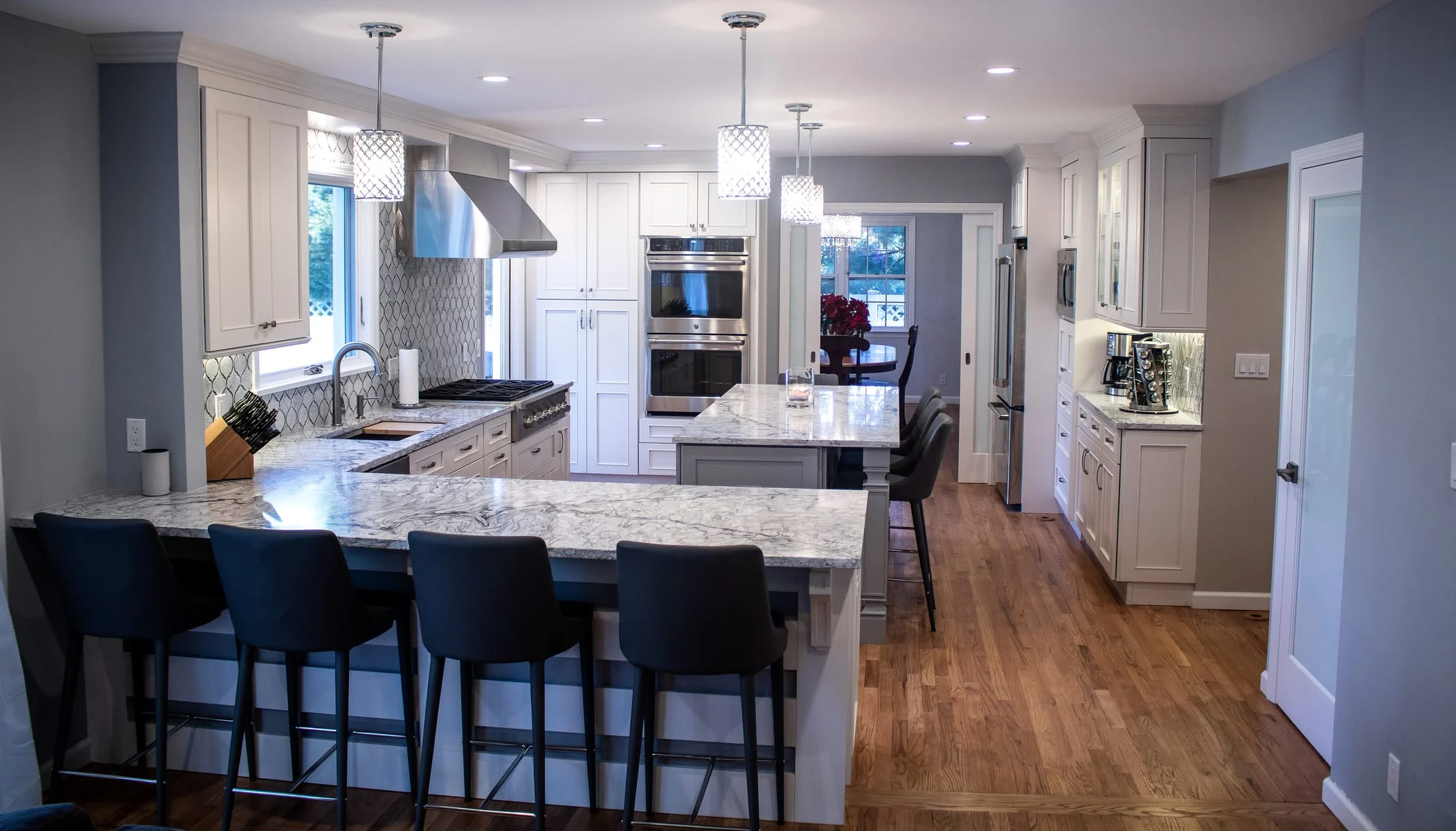Kitchen with large island seating, white cabinetry, and pendant lighting