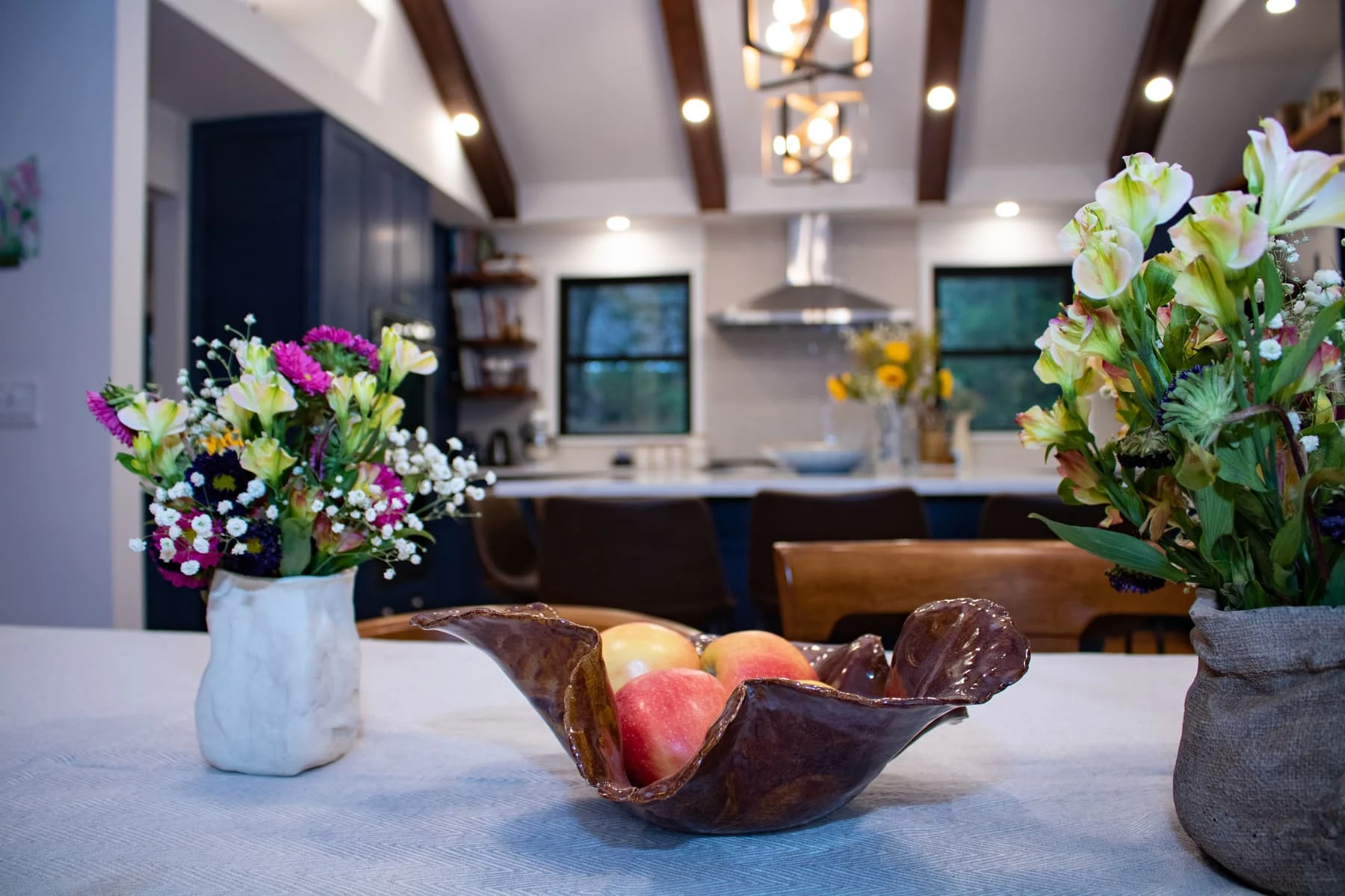 Kitchen with wood beams, blue cabinetry, and island seating in Chappaqua home