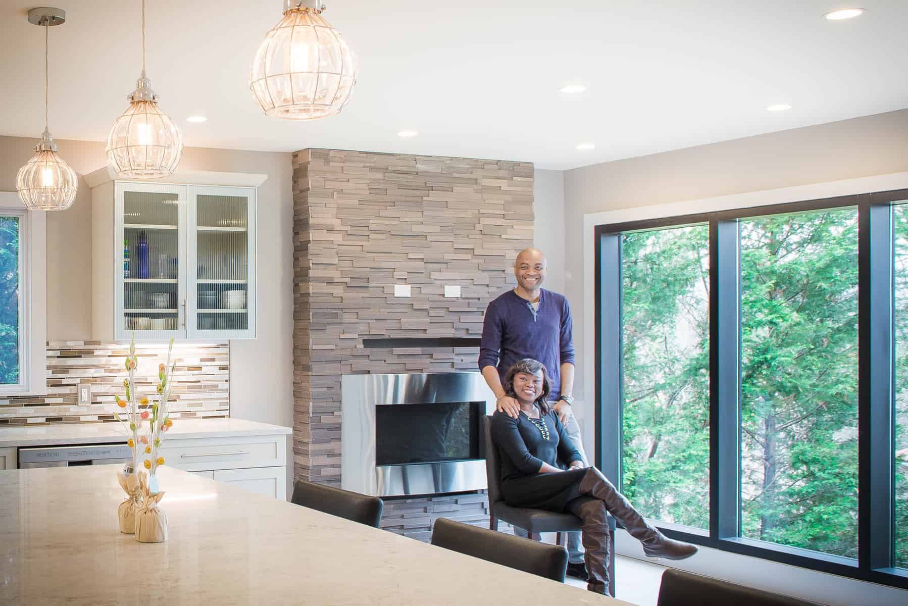 Open-concept kitchen and living space with stone fireplace and large windows